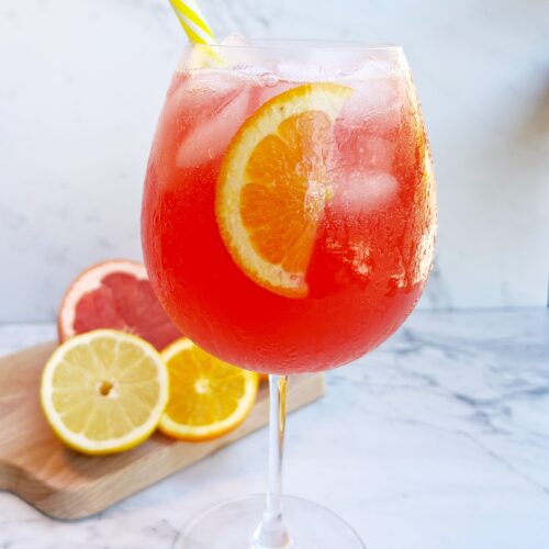 Refreshing Passion Spritz with passion tea, orange juice, lemon juice, and sparkling water, served in a glass with fresh fruit garnish