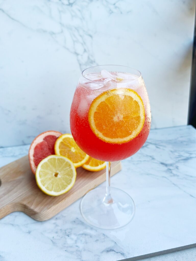 Refreshing Passion Spritz with ice, citrus slices, and a blend of passion tea, orange juice, and sparkling water, served in a clear glass for a summer drink.